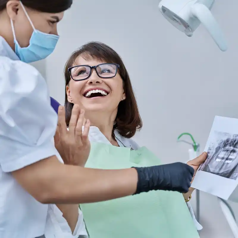 A woman patient smiling while dentist shows her dental imaging